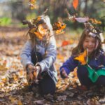 Børn leger i blade i skov
